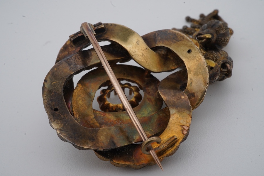 A Victorian opal brooch, mid 19th century, of knotted design in textured gold, set with a cabochon opal, suspending two tassels, length 7cm, gross weight 14 grams